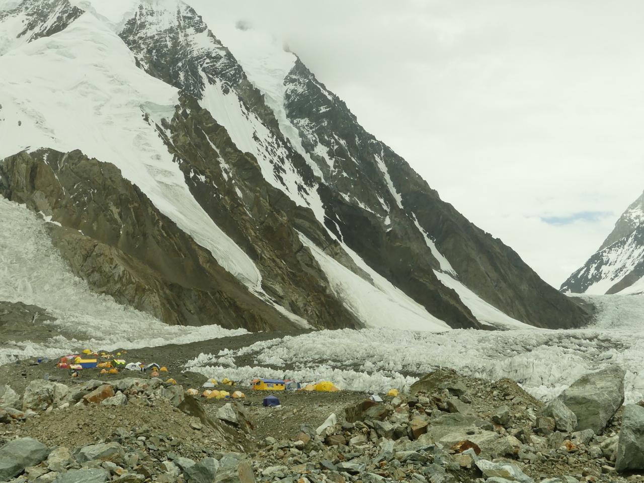 Trekkers walking across the Baltoro Glacier during the K2 Base Camp Trek in Pakistan with K2 mountain visible in the background.